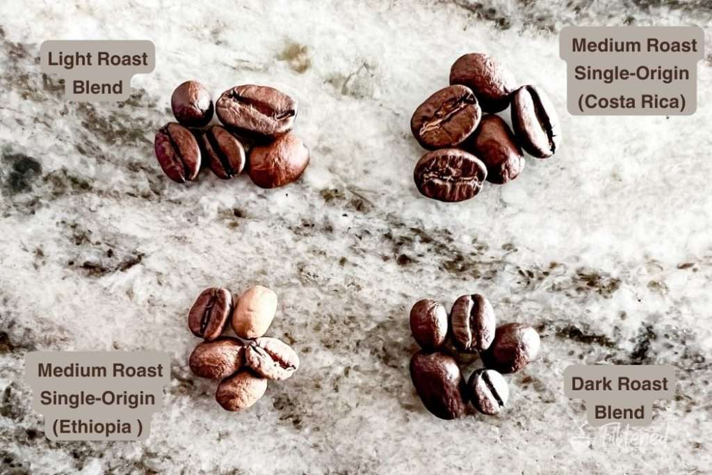 Four piles of coffee beans different in size, roast type, and origin