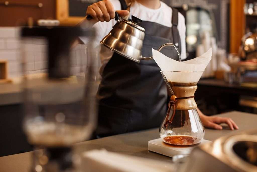 Professional barista in a cafe brewing coffee using a Chemex