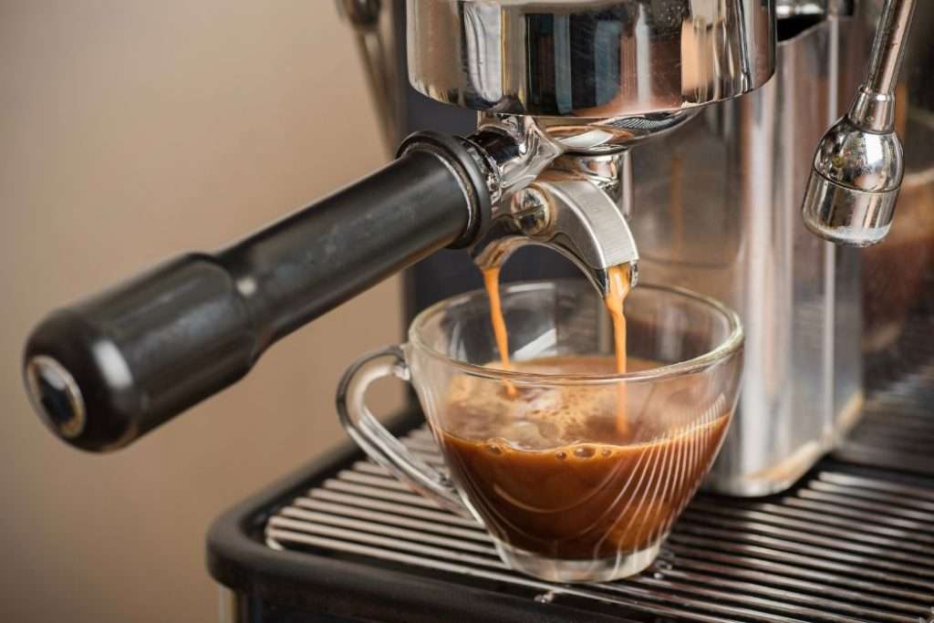 Espresso machine brewing a shot of espresso into a glass coffee cup