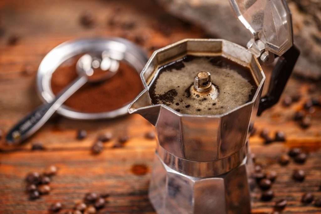 Traditional Italian moka pot filled with coffee sitting on a wooden table