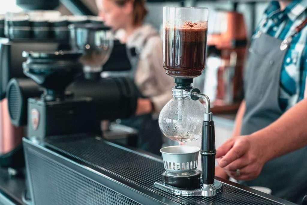 Professional barista making coffee in a cafe using a siphon brewer