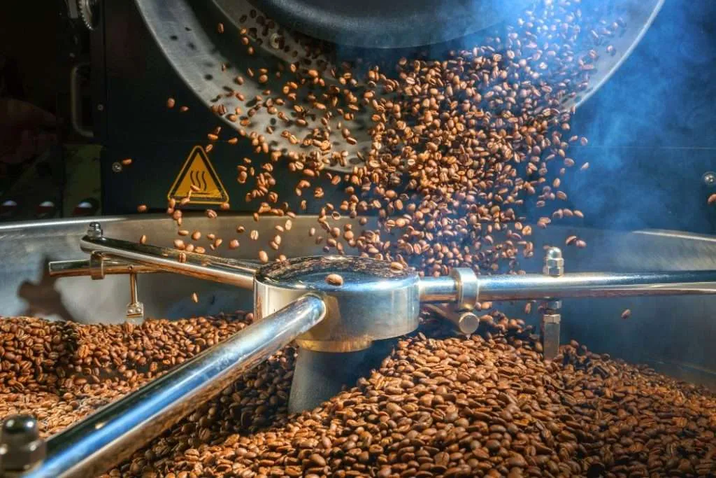 Coffee beans that have finished roasting being dropped into a cooling tray