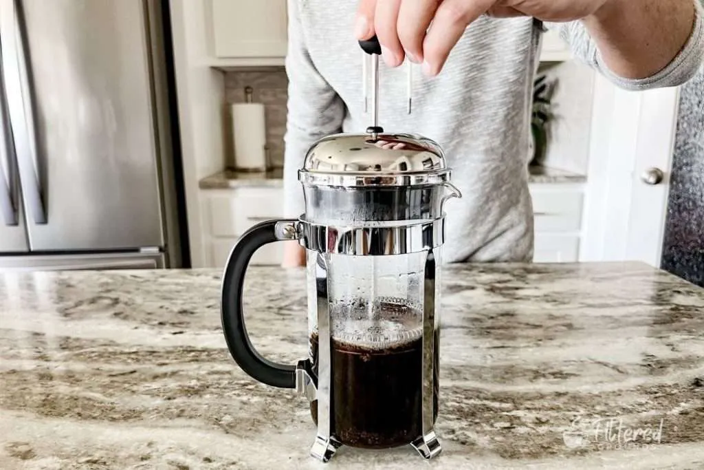 Home barista using a French press to brew coffee