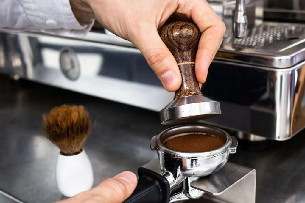 Barista using a tamper to compact coffee grounds in a portafilter