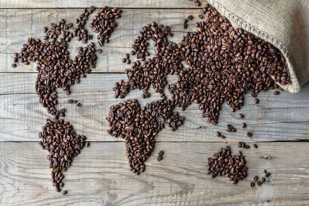 World map made out of coffee beans spilled on a wood table