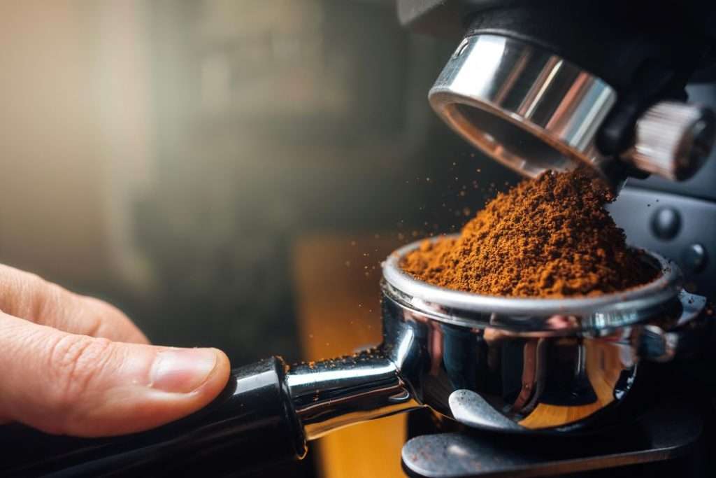 Ground coffee pouring into a portafilter from a grinder