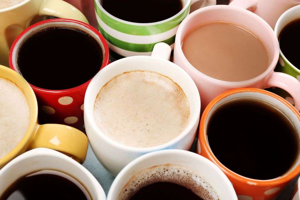 Table filled with different colored coffee cups each filled with coffee